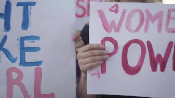 Camera Moves Along Feminist Banners in Activists Hands. Close-up of Women Rights Slogans on Placards