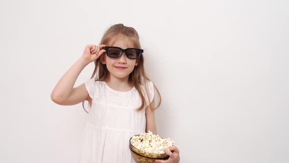 Girl with Glasses to Watch 3D Movies with Popcorn Stands Against White Wall