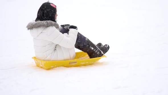 Asian Teen Playing Sled Under Snow Fall