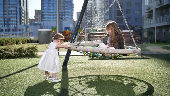 One Year Old Baby Swinging Older Sister Outdoor