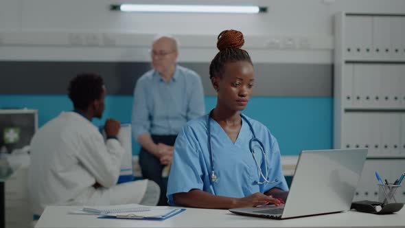 Portrait of Nurse Typing on Laptop Keyboard in Medical Office