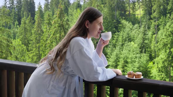 Beautiful Smiling Woman Relaxing at Hotel Wearing Bathrobe and Having Breakfast on Summer Terrace