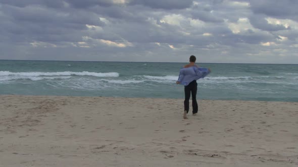 Male taking his suit off and running into an ocean