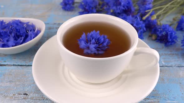 Brewing a tisanes from knapweeds flowers in white cup.