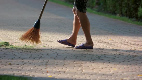 Sweeping Cut Grass From Cobblestone Pavement.