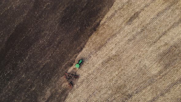 Aerial view, drone view of green tractor with plough working on a field,