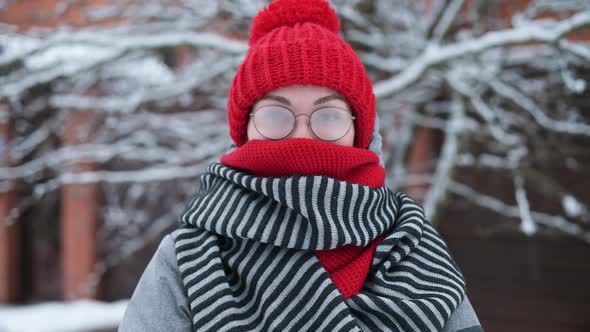 Portrait of a young woman in misted glasses outdoors on a frosty snowy day