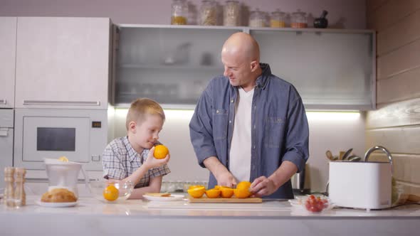 Father and Son Cutting Oranges in Kitchen