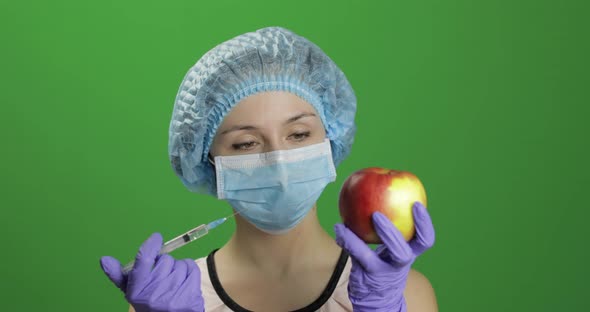 Female Scientist Makes a Injection with a Medicine Syringe in Apple