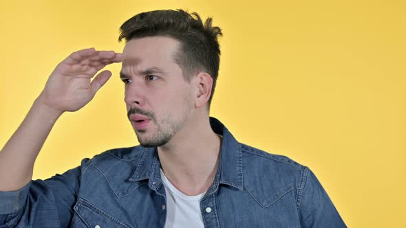 Portrait of Ambitious Young Man Searching for Opportunities, Yellow Background