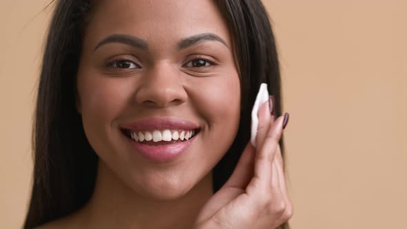 African Woman Using Cotton Pad Applying Face Powder Beige Background