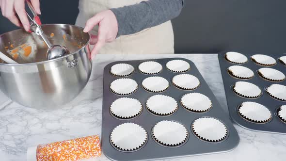 Time lapse. Scooping pumpkin spice cupcake batter with batter scoop into a cupcake pan with liners.