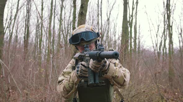 Armed Young Man in a Zone of Armed Conflict in Uniform Targeting with Assault Rifle Walking in