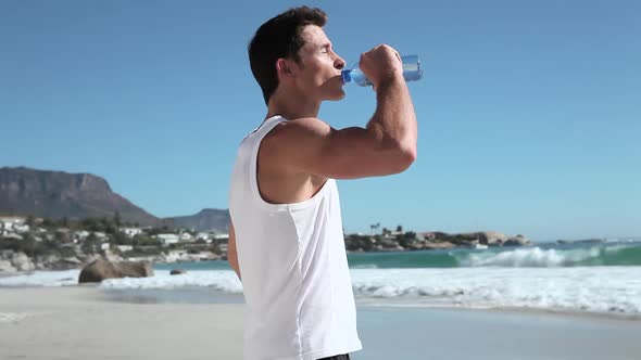 Young man drinking water on beach