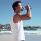Young man drinking water on beach - VideoHive Item for Sale