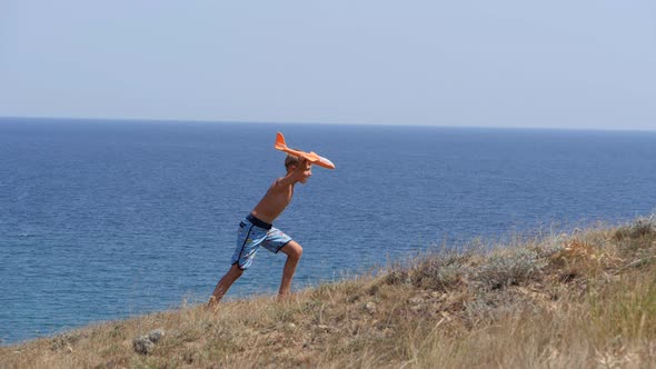 Boy with a Toy Airplane in His Hands on the Background of the Sea