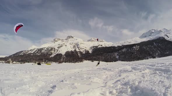 A young man snow kiting on a snowboard.