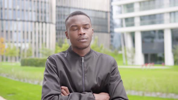 A Young Black Man Thinks About Something - Office Buildings in the Blurry Background