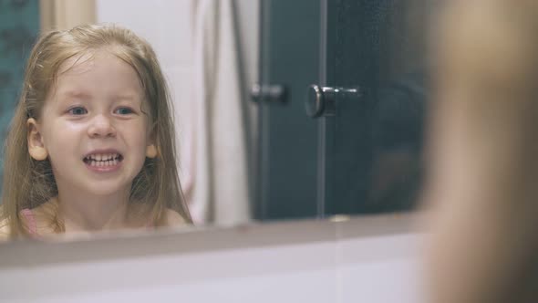 Little Girl Looks at Clean Teeth and Screams at Large Mirror