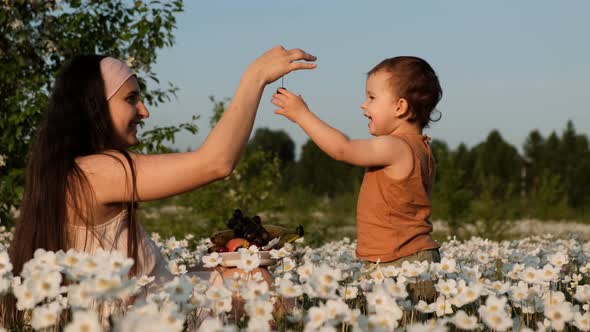 A Young Mother Feeds Her Young Son Cherries