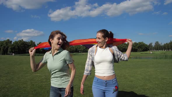 Joyful Gay Couple with Pride Flag Running Outdoors