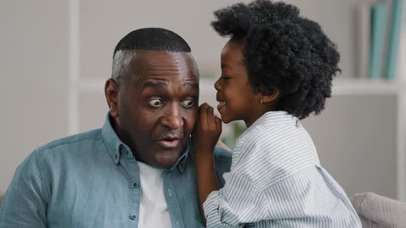 Little African American Daughter Whispering Secret Adult Dad in Ear Telling Gossip Surprised Dad