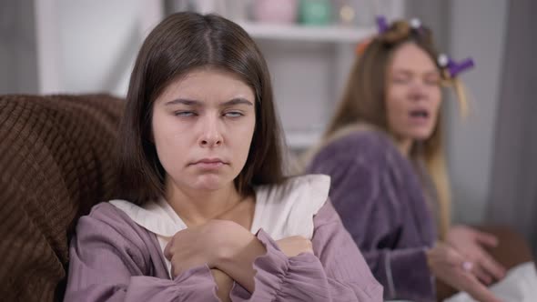 Portrait of Annoyed Young Woman with Irritated Facial Expression Looking at Camera As Blurred Friend