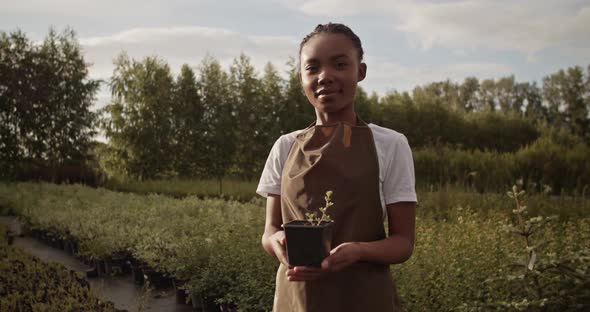 Young Black Farmer with Potted Plant in Countryside