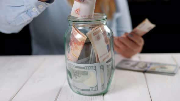 Closeup of a Young Woman Puts Five Thousand Rubles in a Glass Jar