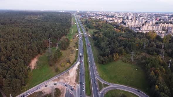 Drone flying towards Kaunas city residential district over the A1 highway with heavy traffic and ped