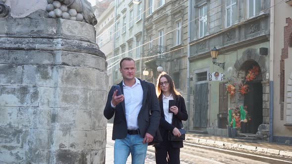 Two Business People a Man and a Woman Go to a Meeting Talk on the Phone in the Morning