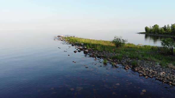 Round stones, transparent water and green grass, aerial shot of cape