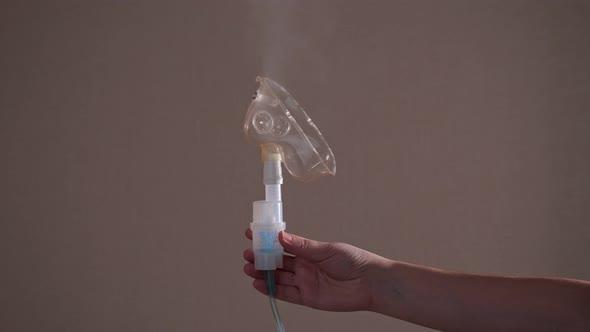 Woman's Hand Holds a Nebulizer From Which Steam Comes Out