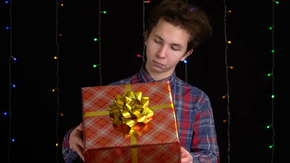 Boy with a Gift Box on Black Background. Gift Box with Ribbon for Happy New Year, Merry Christmas