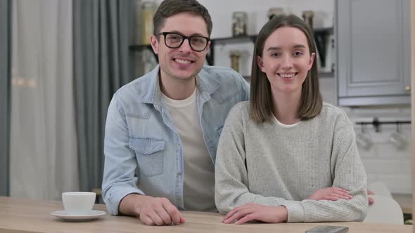 Cheerful Young Couple Smiling at Camera in Living Room