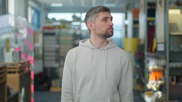 Handsome Concentrated Man Looking Around Standing in Hardware Store and Thinking