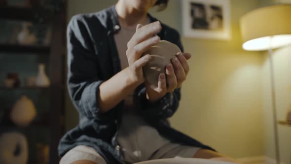 Young Female Potter in Workshop Crumples and Claps a Lump of Clay with Her Hands