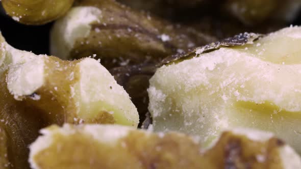 Macro shot, skin of peeled walnuts rotating over black surface background. Close up shot.