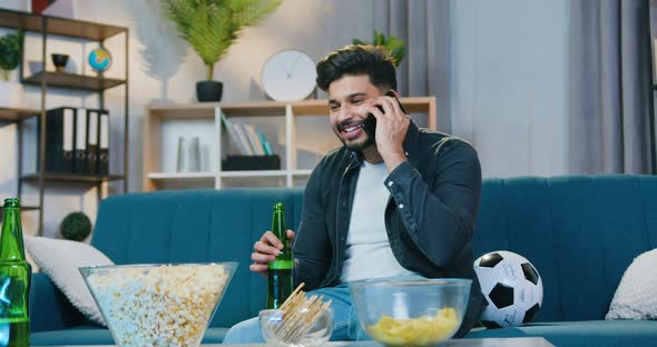 Guy Enjoying Pleasant Mobile Conversation when Sitting on the Couch at Home