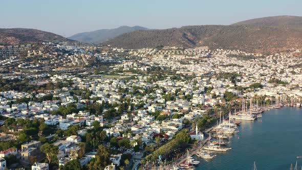 aerial drone panning across the coastal town of Bodrum as the sun sets over the white villas and hil