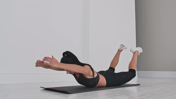 Young Attractive Woman in Double Leg Kicks Exercise Grey Studio