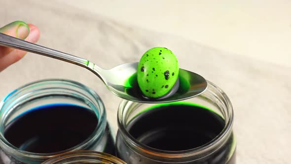 a Child Holds in a Metal Spoon a Green Dyed Easter Quail in a Dotted Egg on Glass Jars with