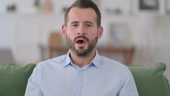 Sick Young Man Sneezing at Home