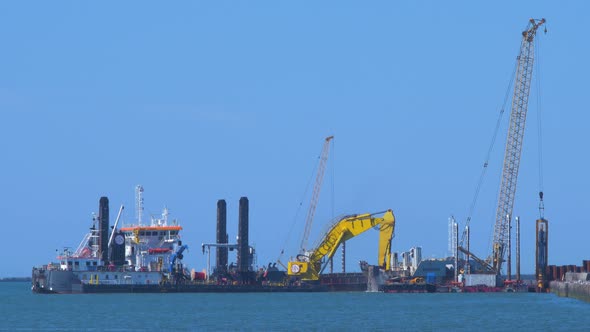 Hopper dredger ship working at Port of Liepaja, crane with bucket lifts up soil from the bay, medium