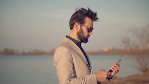 Businessman In Suit Chatting On Mobile Phone With Friend  Sending Message On Social Network.