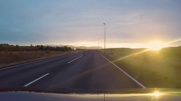 Driving towards the sunset and mountains in West Iceland from the perspective of a vehicle