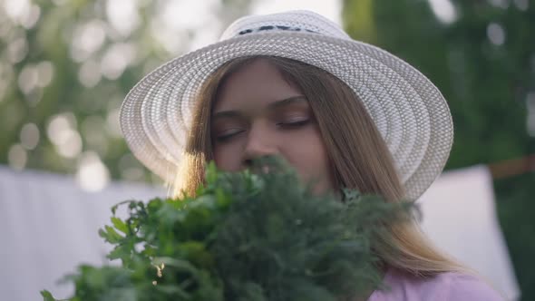 Closeup Portrait of Satisfied Young Female Gardener Smelling Greenery Smiling