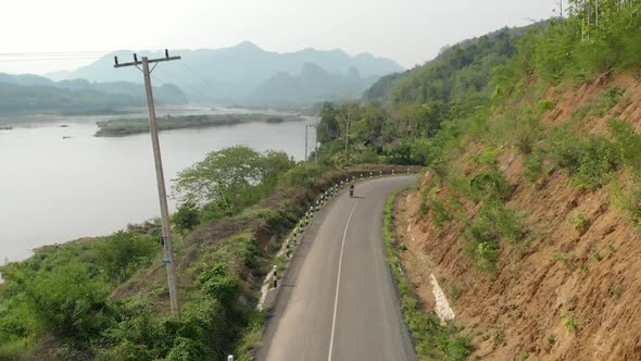 Aerial view of Motorcyclist on road next to Mekong River, Laos 