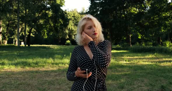 Dreamy pretty girl listening to music in the park