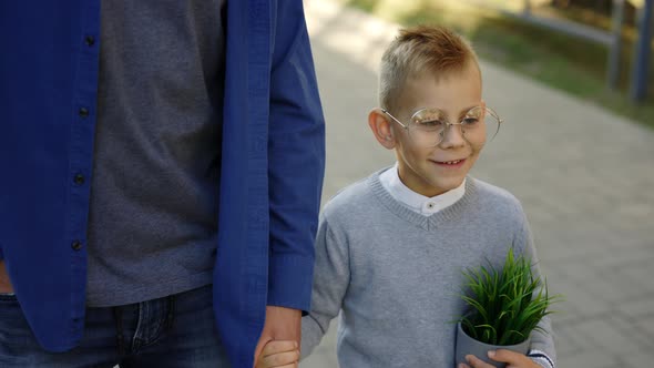 Father Holding Son Hand and Child is Holding the Plant in a Pot Telling Father Stories From School